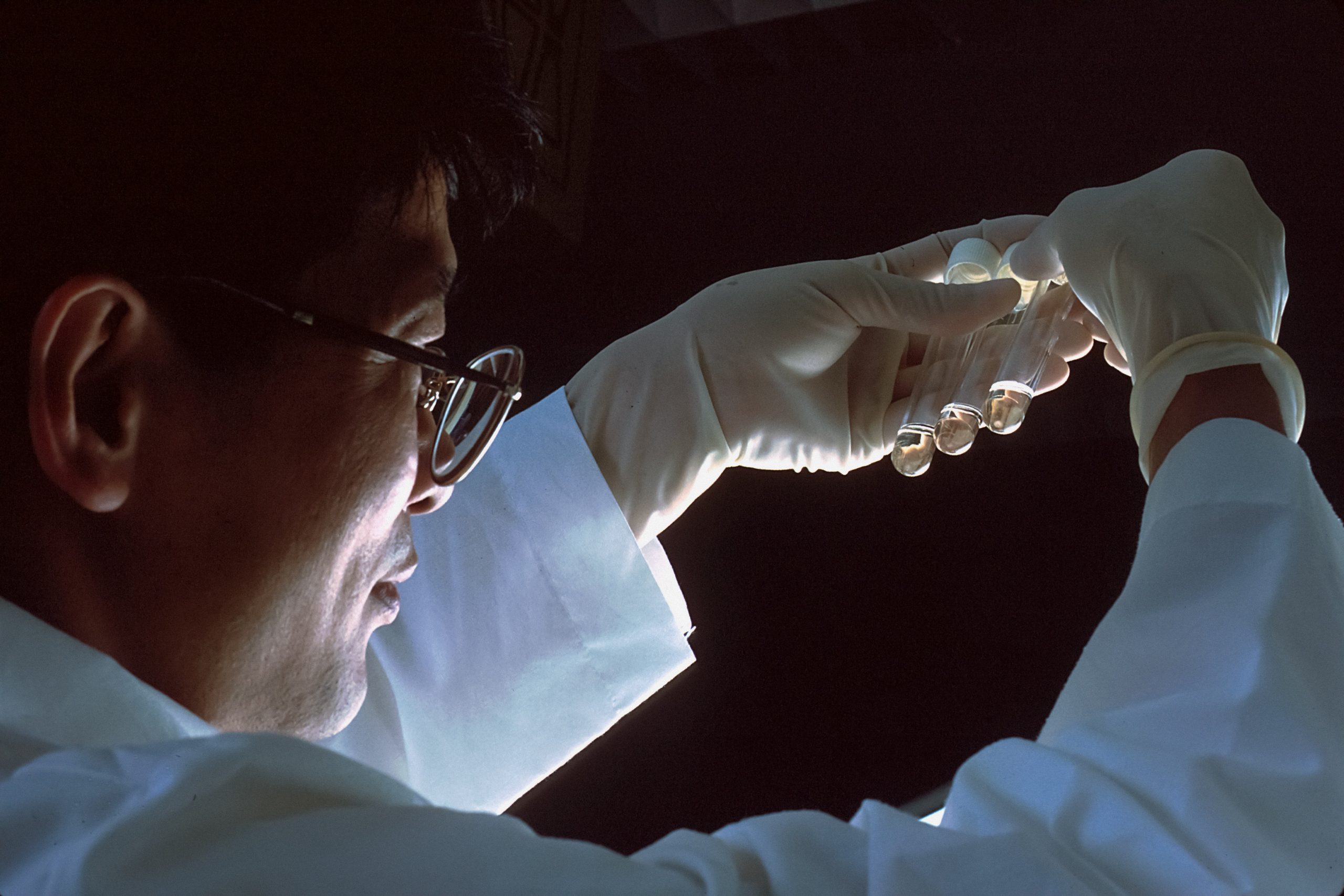 A male scientist holding three test tubes. The test tube on the right contains t-lymphocytes that were exposed to the AIDS virus but since they were protected by AZT, the cells were not destroyed and the pellet stayed intact.